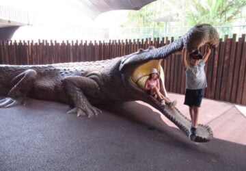 Two children in the mouth of a large crocodile statue at Australia Zoo.