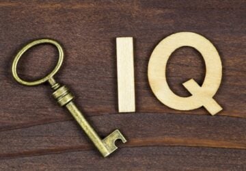 Wooden background with gold key on it and gold letters I and Q together to read IQ