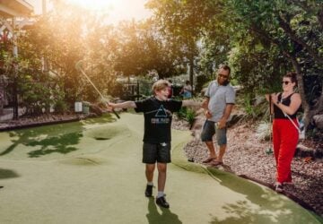 Victoria Park family playing putt putt outdoors.