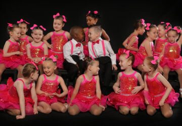 Group of children on stage during ballet performance in pink outfits