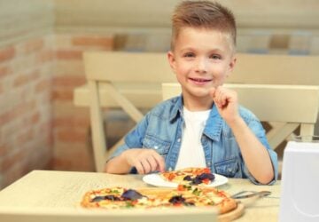 Boy eating pizza at a table.