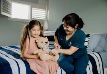 Childrens Nursing Queensland staff with child sitting on bed.