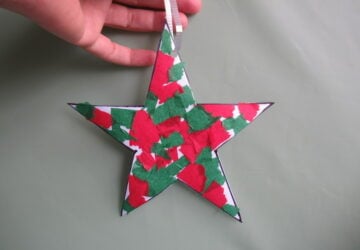 A hand holding a paper star with red and green paper on it.