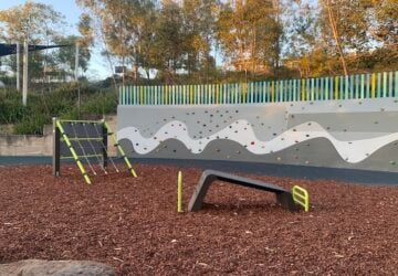 A long rock climbing wall and outdoor gym equipment at Fenwick Park.