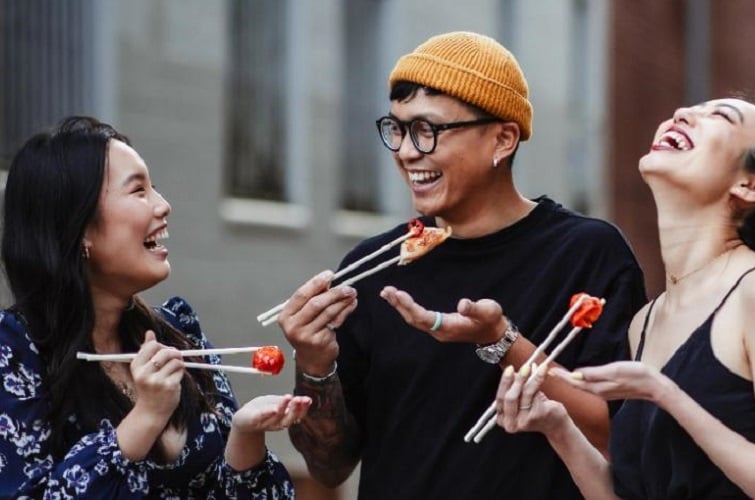 Fish Land Asian Street Festival event image of people eating sashimi with chopsticks in lane way.