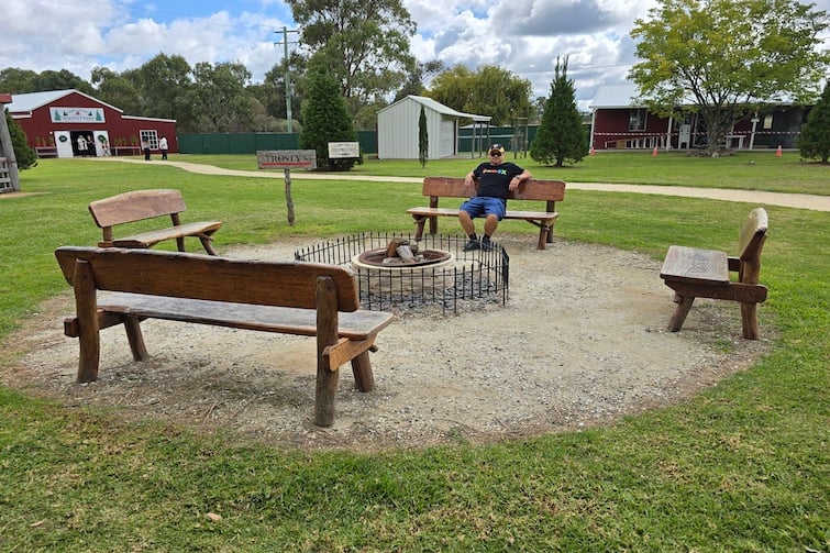 A man sitting around a fire ring at Granite Belt Christmas Farm.