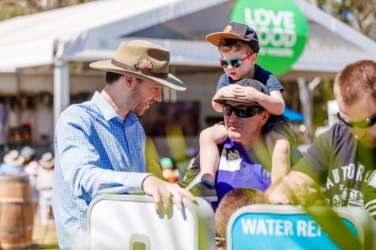 green heart fair child on dads shoulders looking at displays