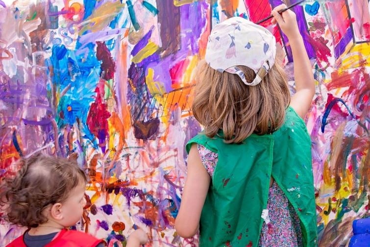 Imagination festival event image of two kids painting on a mural.