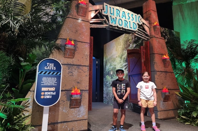 Two children standing in front of the Jurassic World gates at Jurassic World by Brickman.