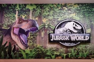 Promotional sign of a dinosaur and Jurassic World symbol at Jurassic World by Brickman.