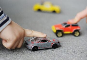 Two little fingers touching toy race cars.
