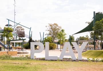 logan village playground play sign with playground behind