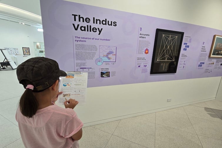 A girl holding a clipboard and looking at the display at The Mathema Gallery.
