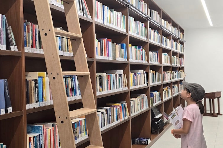 A young girl looking at the shelves of books in the library at The Mathema Gallery.