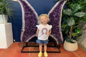 Little girl standing in front of amethyst wings at Opals Down Under.