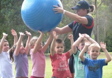 Physi kids young children and instructor with large ball.