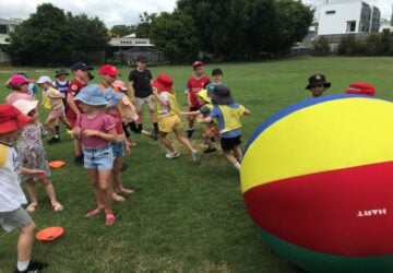Q Kids Sport parties group of children playing outdoors with giant ball.