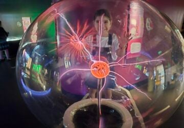 Young girl touching the plasma globe at SparkLab at the Queensland Museum.