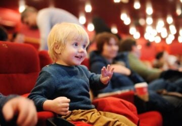 Toddler at theatre smiling waving.