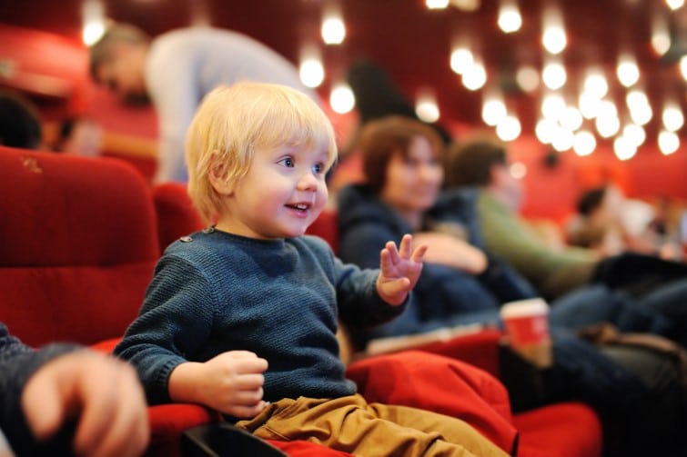 Toddler at theatre smiling waving.