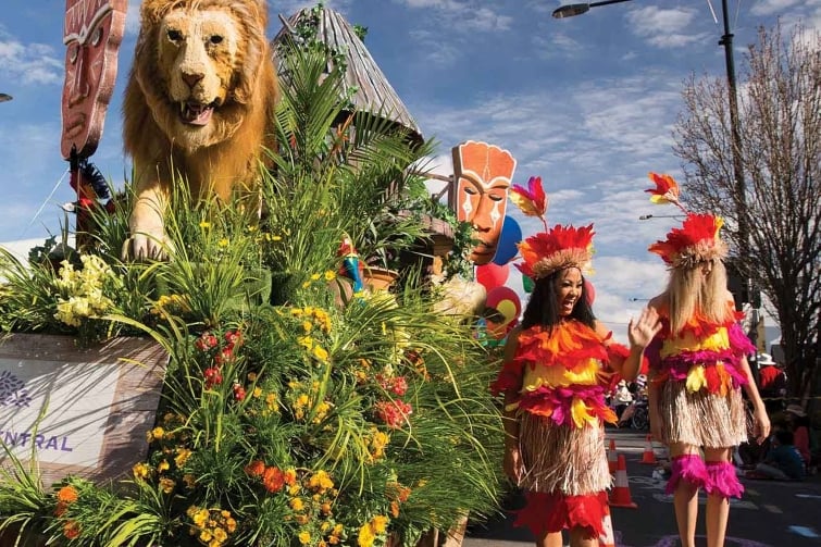 Toowoomba carnival of flowers event image of lion on flower float and girls walking beside in the grand parade.