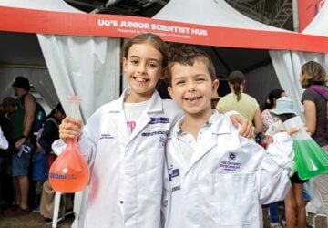 Two children in white lab coats holding beakers - World Science Festival Brisbane 2024.