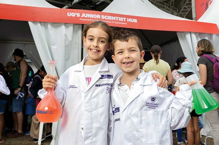 Two children in white lab coats holding beakers - World Science Festival Brisbane 2024.