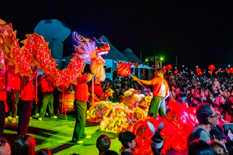 BrisAsia Lunar New Year Rooftop Party event image of dragon dancing on stage and crowd.